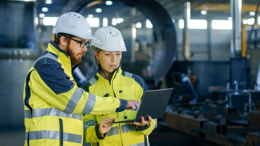 Two workers looking at an laptop on work site.